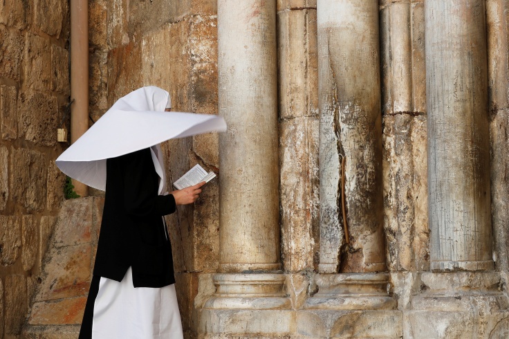 A nun prays in front of the closed front door of the Church of the Holy Sepulchre amid coronavirus restrictions in Jerusalem's Old City